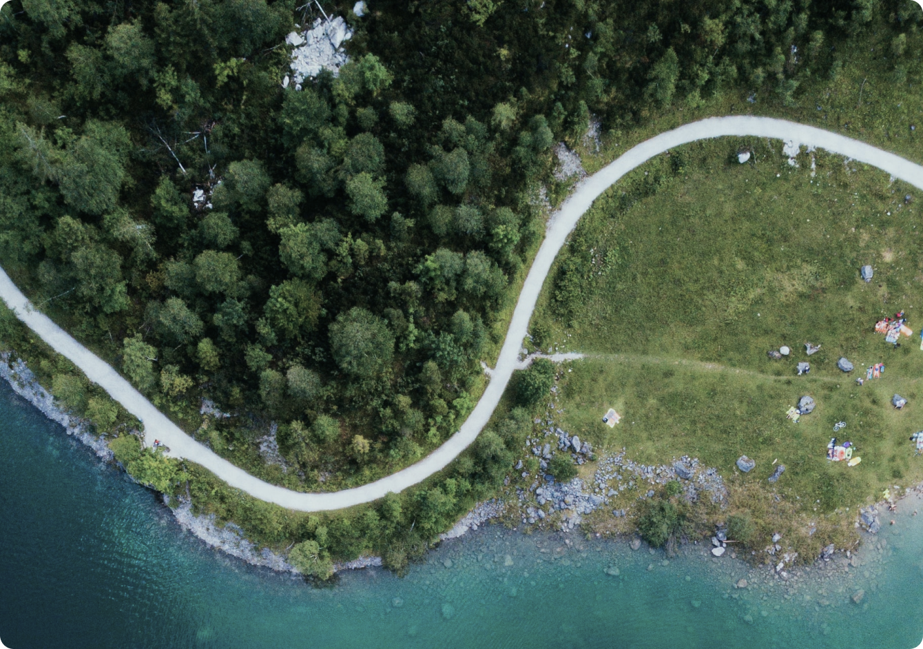 空撮で見た、曲がりくねった川沿いのキャンプ場。緑豊かな樹木に囲まれ、透明な水が流れる